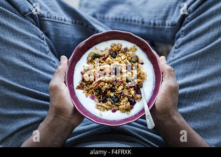 Un bol de Granola citrouille épicée est entre les mains d'un homme. Banque D'Images