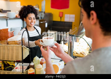 Waitress serving cappuccino pour client Banque D'Images