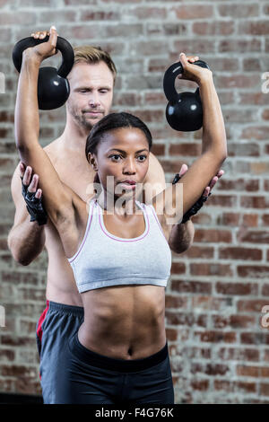 Woman lifting kettlebells avec son entraîneur Banque D'Images