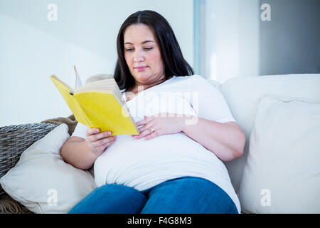 Smiling pregnant woman reading a book Banque D'Images