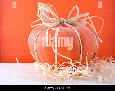 Citrouille peinte moderne décoré avec voûte rafia et de paille sur table en bois blanc et orange fond bois pour Thanksgivng Banque D'Images