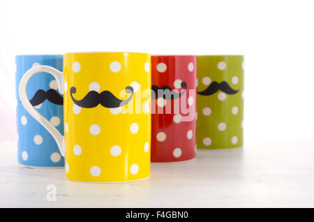 Tasses à café à pois colorés avec des moustaches pour novembre Mens Health Awareness sur table en bois blanc. Banque D'Images