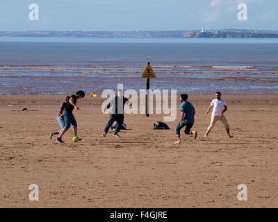 Groupe multi-raciale de jeunes hommes jouent au football sur la plage, Weston-super-Mare, Somerset, UK Banque D'Images