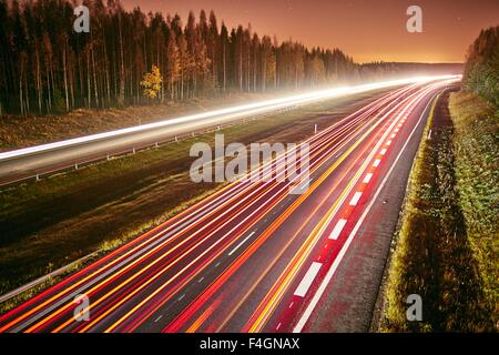 Les sentiers de la lumière des voitures sur une route de nuit. Une longue exposition de la circulation en mouvement rapide sur une nuit étoilée. Banque D'Images