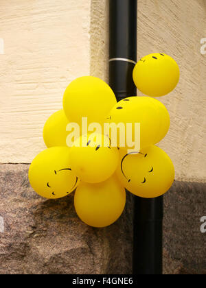 Un bouquet de ballons jaunes avec des visages heureux lié à une gouttière à Tallinn, Estonie Banque D'Images