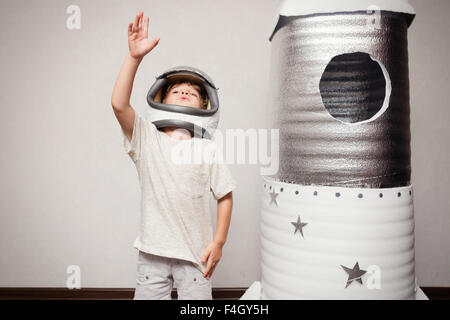 Heureux l'enfant habillé en costume d'astronaute en jouant avec la fusée. Banque D'Images