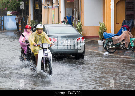 Cyclistes de scooter pendant octobre pluvieuse à Hoi an, ancienne ville au Vietnam sur la côte centrale, Asie, 2015 Banque D'Images