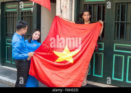 Mariage vietnamien à Hanoi old quarter, couple heureux de poser pour des photos dans la rue, drapeau national du Vietnam tenant Banque D'Images