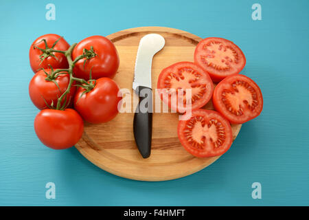 Tomates mûres de coupe avec un couteau à tomates sur planche à découper en bois Banque D'Images