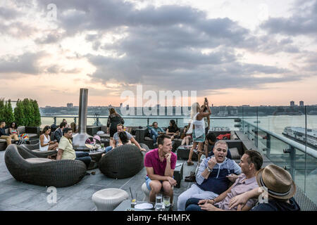 Les gens détendue prendre un verre et socialiser vue du coucher de soleil de la rivière Hudson bar sur le toit-terrasse de l'encre de Manhattan Banque D'Images