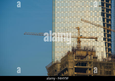 Site de construction d'un nouveau bâtiment avec des grues à tour et le glasfacade d'un immeuble derrière Banque D'Images