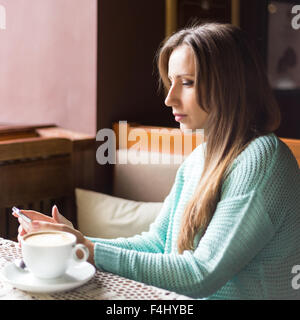 Portrait de belle jeune femme en utilisant son téléphone portable dans le café. Banque D'Images