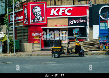 La façade rouge d'un Kentucky Fried Chicken, KFC, restaurant avec un moteur rikshaw parking en face Banque D'Images