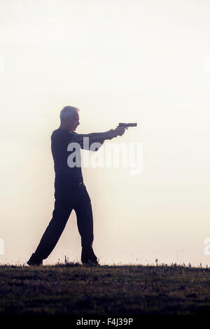 Silhouette d'un homme avec une arme à feu Banque D'Images