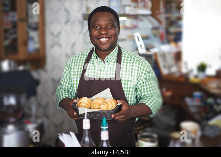 Jeune homme en uniforme la tenue des croissants frais Banque D'Images