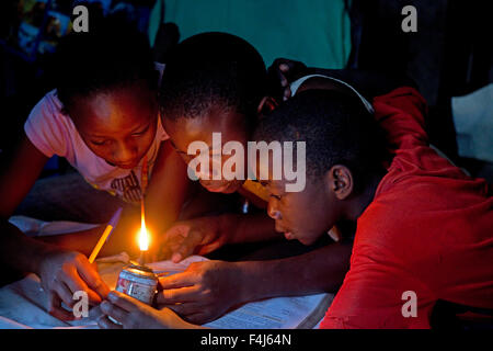 Les enfants africains d'essayer de lire livre avec lumière kérosène Kamere Lake Naivasha au Kenya Banque D'Images