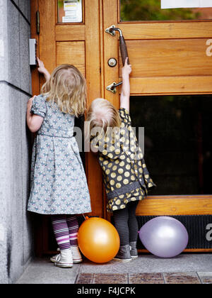 La Scandinavie, la Suède, Stockholm, poussant les filles porte, vue arrière Banque D'Images