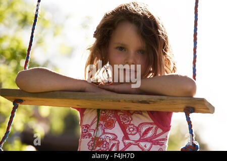 Girl leaning on board of swing Banque D'Images