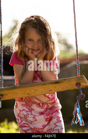 Girl leaning on board of swing Banque D'Images