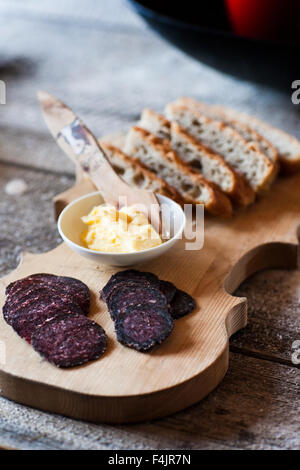Close up of pain, beurre et de tranches de saucisse sur une planche à découper Banque D'Images