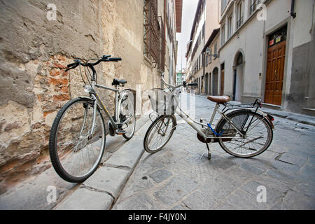 Deux vélos garés sur les stands dans la rue vide, Florence, Italie Banque D'Images