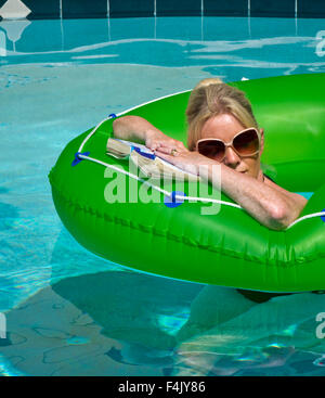 Femme en vacances de détente sur un anneau de caoutchouc dans une piscine Banque D'Images