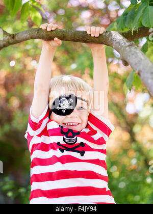 Boy wearing eye patch accroché à partir de la branche de l'arbre Photo  Stock - Alamy