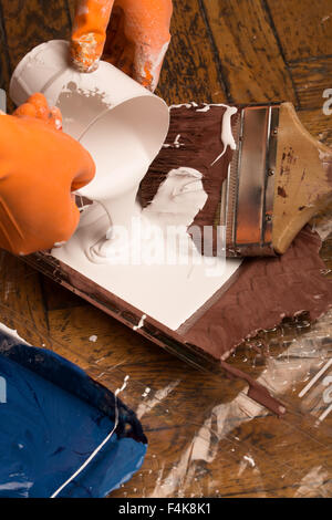 Bouteille de peinture et les pinceaux sur le plancher avec les taches de peinture multicolore Banque D'Images