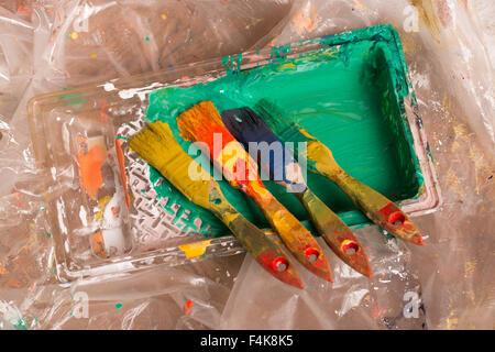 Bouteille de peinture et les pinceaux sur le plancher avec les taches de peinture multicolore Banque D'Images