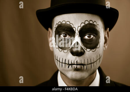 Portrait d'un homme avec le maquillage, le port de calaveras et veste top hat, contre un fond brun Banque D'Images