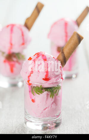 Boules de crème glacée aux fraises en verrines avec gaufre sur fond de table vintage en bois. Banque D'Images