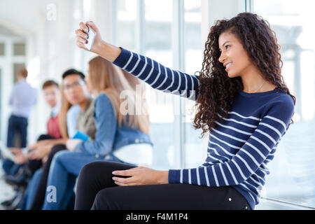 Portrait of a smiling afro american woman photo selfies sur smartphone dans university hall Banque D'Images