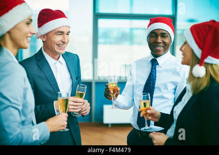 Les travailleurs de bureau moderne à Santa casquettes célébrant Noël après le travail Banque D'Images