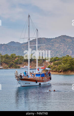 Les personnes qui prennent un bain dans la mer tandis que la goélette en bois bateau est ancré pour le déjeuner sur le 12 tour de l'île hors de Fethiye, Turquie. Banque D'Images