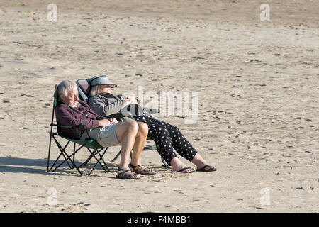 Un couple de personnes âgées bénéficiant du soleil sur une plage britannique vide, England, UK Banque D'Images