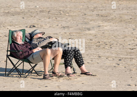 Un couple de personnes âgées bénéficiant du soleil sur une plage britannique vide, England, UK Banque D'Images