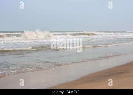 Les vagues de la mer écumeuse élevée sur une plage tropicale dans la soirée. Banque D'Images