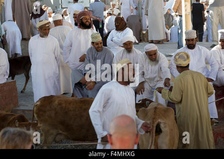 Les hommes omanais sourire et rire en regardant l'élevage pour la vente à l'Nizwah Jeudi Jour de marché. Banque D'Images