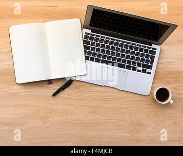 Un ordinateur portable avec un stylo et un bloc-notes avec lumière tasse de café sur une table en bois. Photo avec l'espace pour votre texte. Banque D'Images