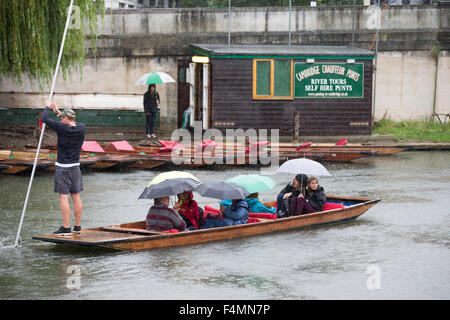Les gens en barque sur la rivière Cam à Cambridge dans la pluie sous des parasols. Banque D'Images