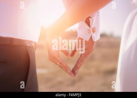 Main dans la main avec les anneaux de mariage sur l'arrière-plan de la lumière du soleil Banque D'Images