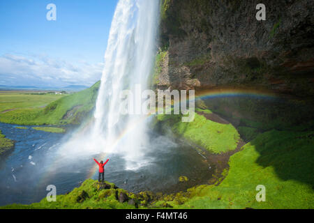 Personne et rainbow sous 60m de haut, la cascade de Seljalandsfoss Sudhurland, Islande. Banque D'Images