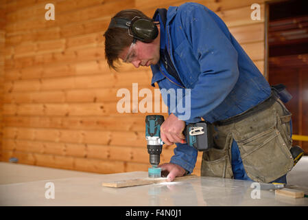 Un constructeur fore un trou dans un mur avant l'installation dans une salle de bains Banque D'Images