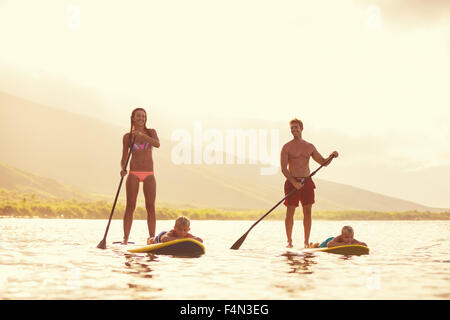 Family Stand up Paddling au lever du soleil d'été, de vie en plein air Banque D'Images