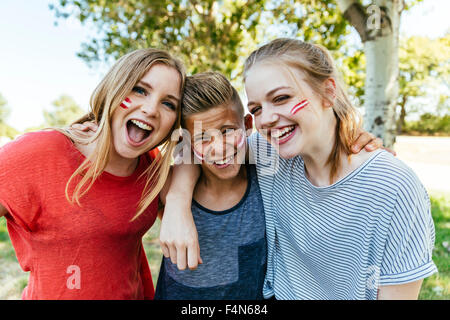 L'Autriche, trois adolescents avec les couleurs peintes sur leurs joues célébrer ensemble Banque D'Images