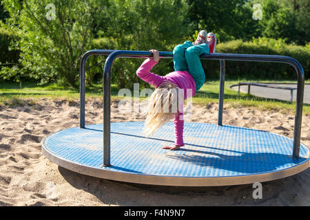 Petite fille blonde jouant sur l'aire de jeux Banque D'Images