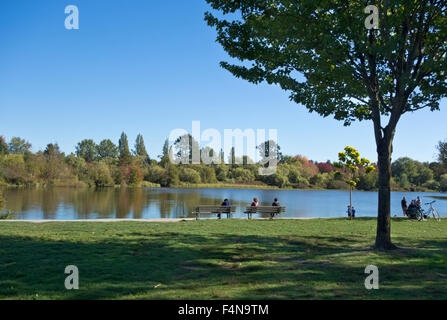 Des gens assis sur des bancs affichage de l'eau à Trout Lake Park dans l'Est de Vancouver. Au début de l'automne d'après-midi. Banque D'Images