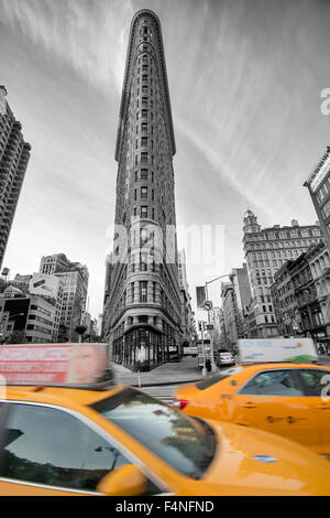 Image couleur sélective de l'emblématique Flatiron Building avec deux taxis jaunes, Manhattan New York USA Banque D'Images