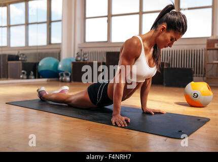 Tapis de sol fitness femme en faisant des exercices d'étirement à la salle de sport. Monter caucasian woman working out at health club. Banque D'Images