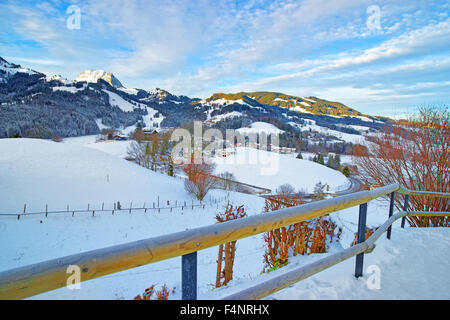 Beau paysage d'hiver avec la neige mountain village sous le bleu ciel nuageux. Le Gruyère dans le canton de Fribourg, Suisse Banque D'Images
